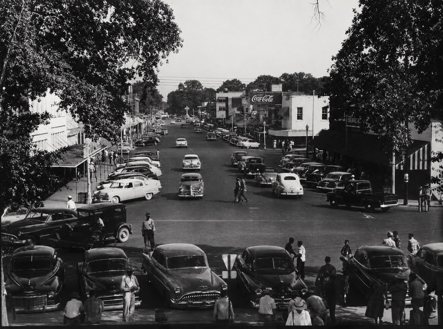 Elevated view down Main Street, Columbia, in the 1950s — cars angle-parked the full length of both sides, a Coca-Cola wall sign, and crowds along the sidewalks. Photograph courtesy of the Marion County Historical Society.