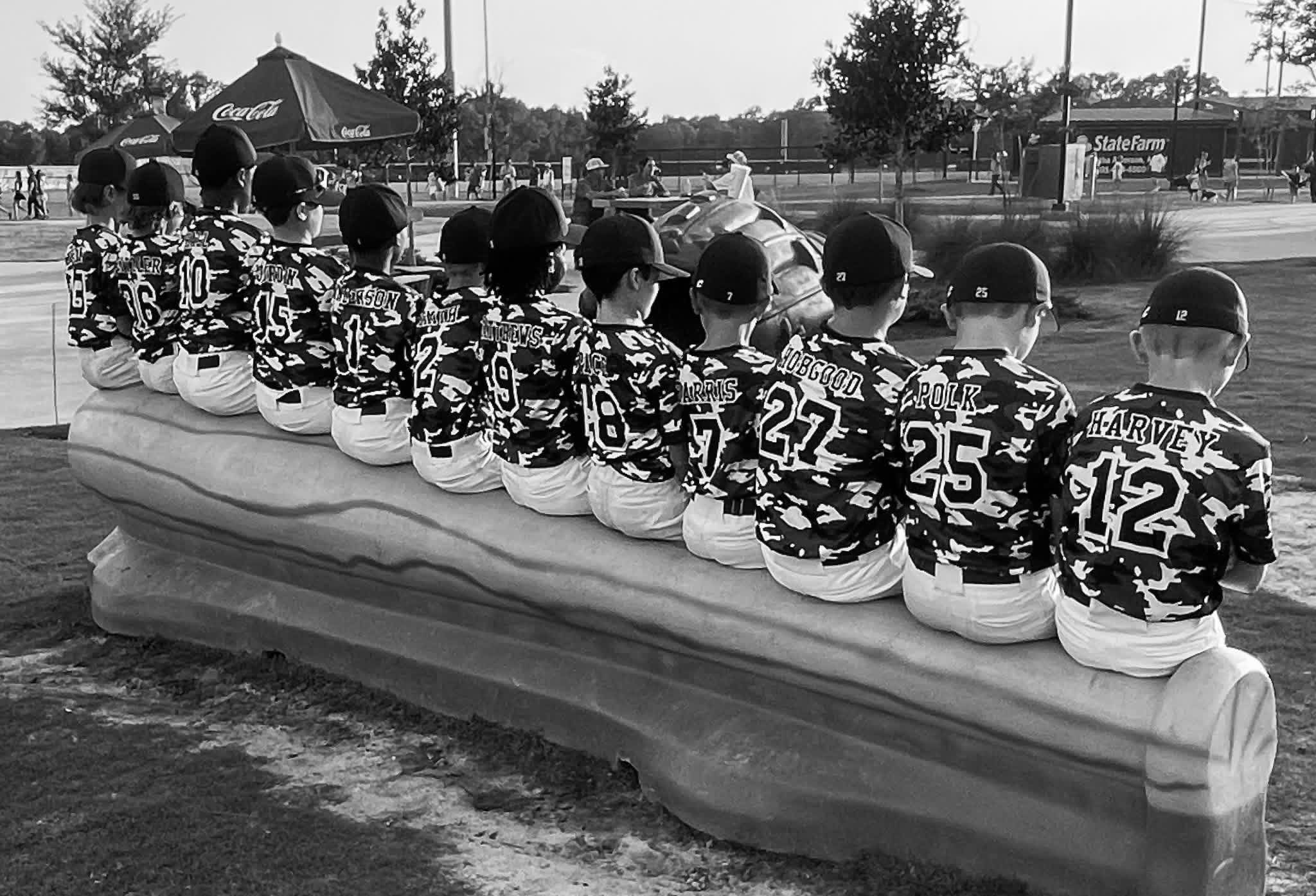 A youth baseball team lined up on the giant bat bench at The Yards