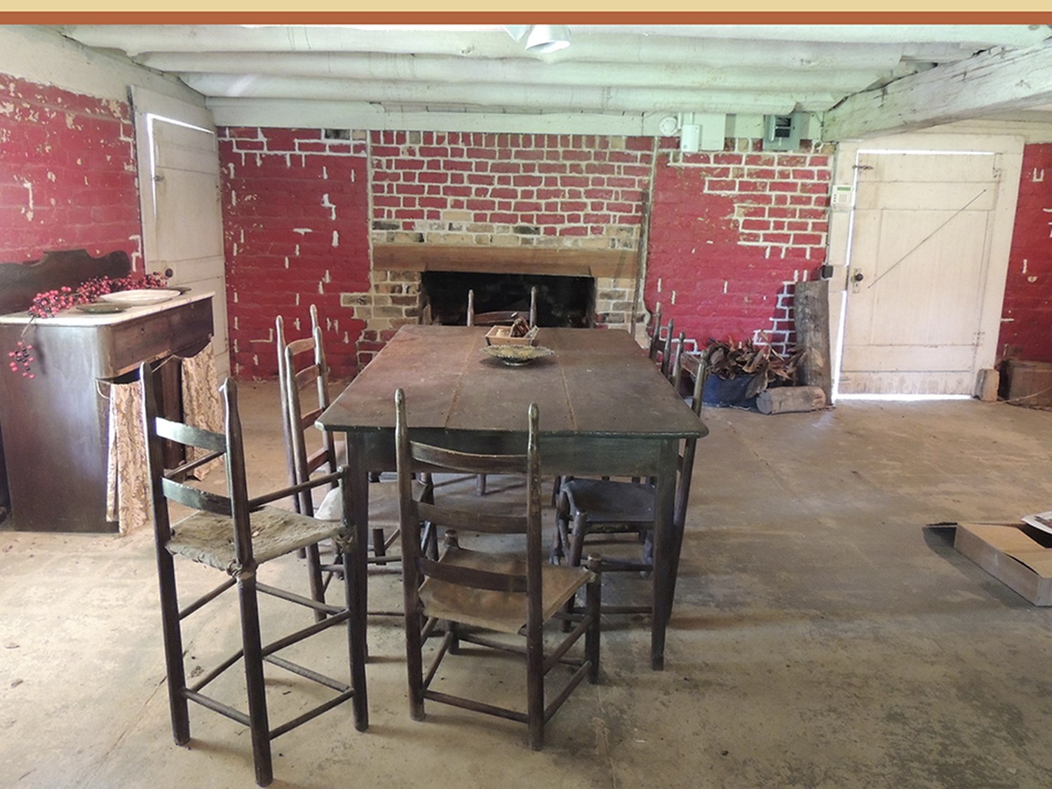 A brick-walled lower room with a long table and chairs set for a meal