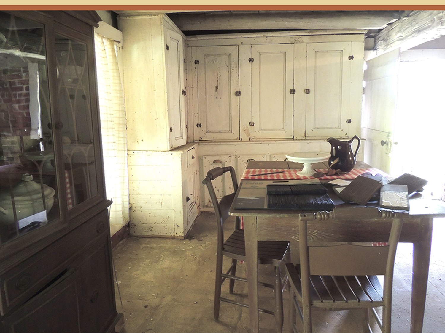 The lower floor kitchen of the John Ford Home with a plank table, ladder-back chairs and a cupboard
